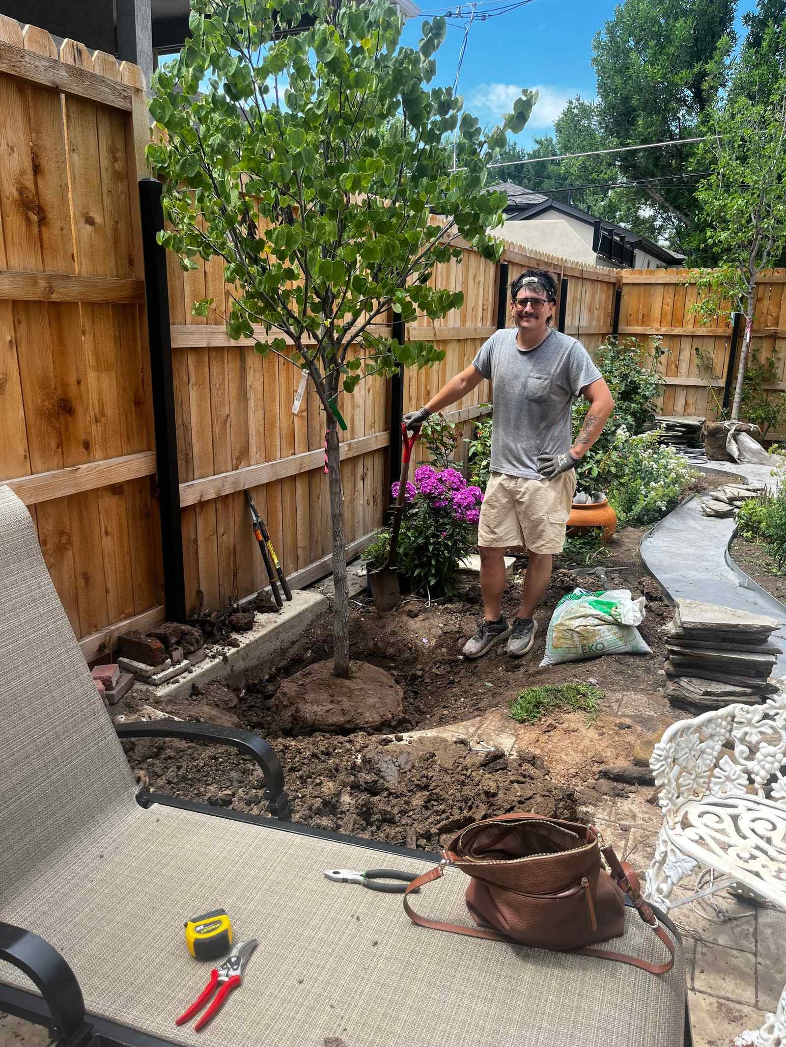 Crew member planting a tree in a backyard, work in progress