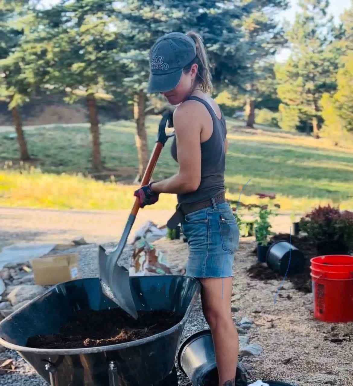 Zoe Simmons with a shovel beside a wheelbarrow